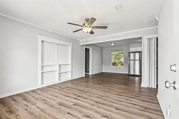 a view of empty room with wooden floor and fan