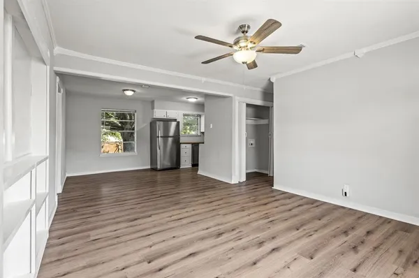 an empty room with wooden floor and a ceiling fan