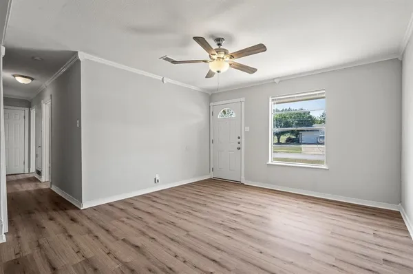 a view of an empty room with wooden floor and a window