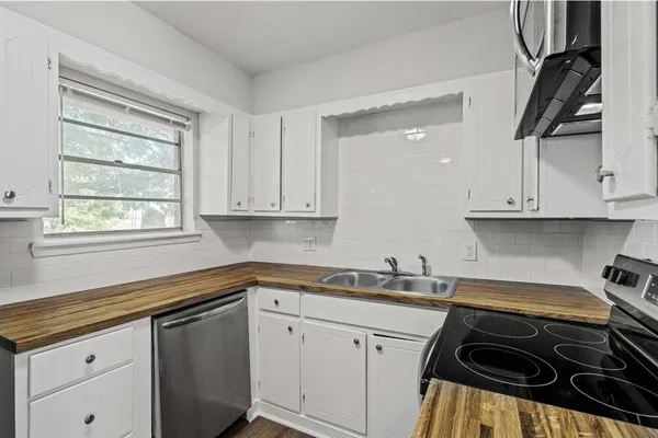 a kitchen with white cabinets appliances and a window