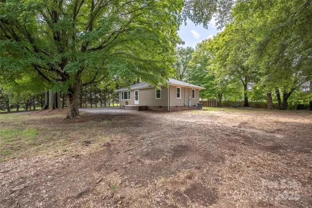 a view of a house with large trees and a small barn