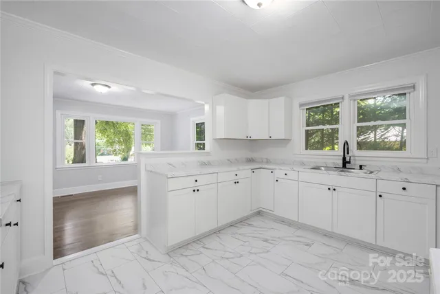 a kitchen with granite countertop white cabinets white appliances a large window and a sink
