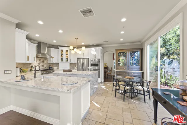 a kitchen with stainless steel appliances kitchen island granite countertop a stove a refrigerator a sink and white cabinets with wooden floor