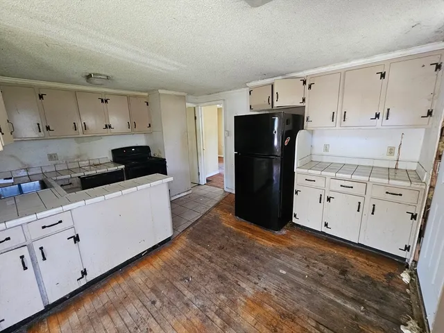 a kitchen with white cabinets and refrigerator