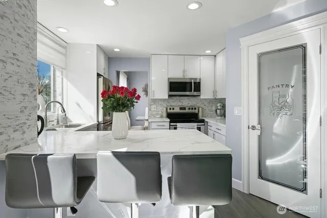 a kitchen with stainless steel appliances a dining table chairs and granite counter tops