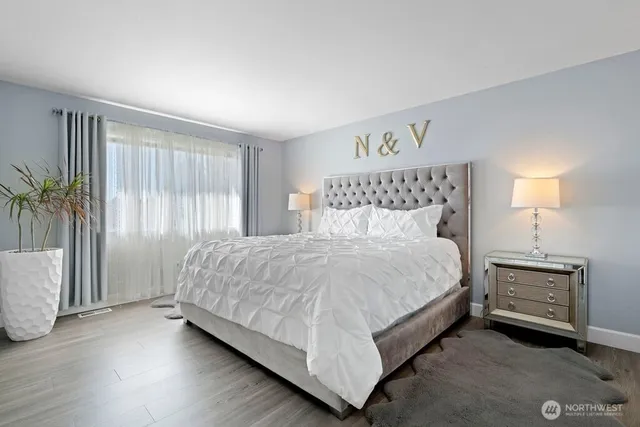 a bed sitting in a spacious bedroom next to a window and a chandelier