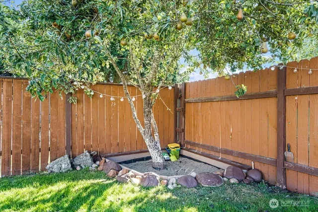 a view of backyard with a fence and a large tree