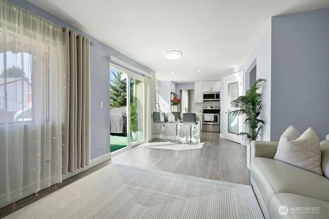 a living room with furniture large window and wooden floor
