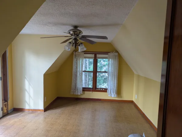 an empty room with chandelier fan and windows