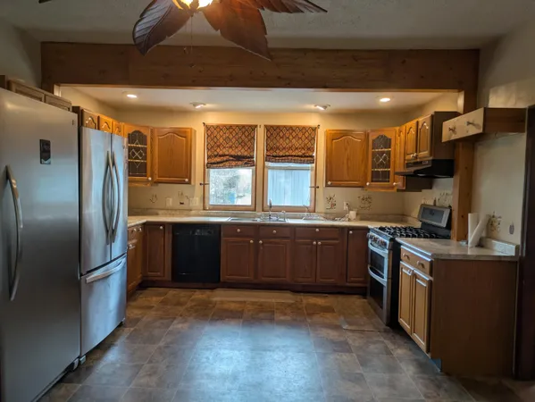 a kitchen with stainless steel appliances granite countertop a refrigerator a sink a stove and oven