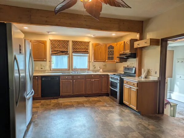 a large kitchen with stainless steel appliances granite countertop a stove a sink and a refrigerator
