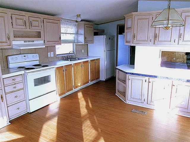 a kitchen with stainless steel appliances granite countertop a stove a sink dishwasher and white cabinets with wooden floor