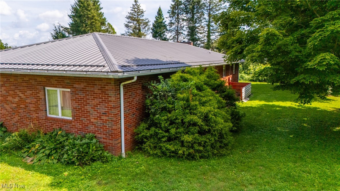 55992 Mt Victory Road Powhatan Point, OH 43942 - Photo 6 of 44 View of home's exterior featuring brick siding, a yard, and a metal roof
