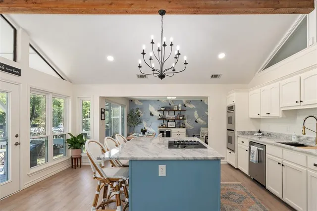 a kitchen with kitchen island granite countertop a center island a sink cabinets and wooden floor