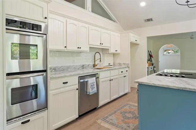 a kitchen with granite countertop white cabinets and stainless steel appliances