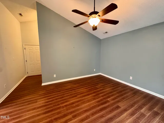 a view of an empty room with window and wooden floor