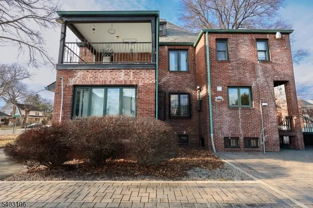 a view of a stone house with a small yard and large tree