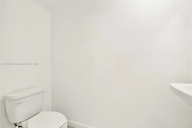 a white toilet sitting next to a white wall