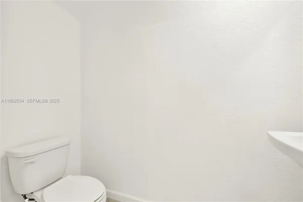 a white toilet sitting next to a white wall