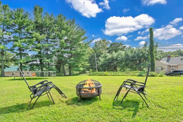 a view of a house with a yard and large trees