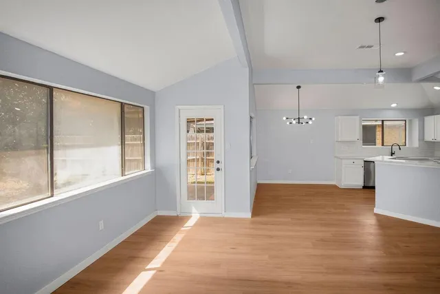 a view of an empty room with a window and wooden floor