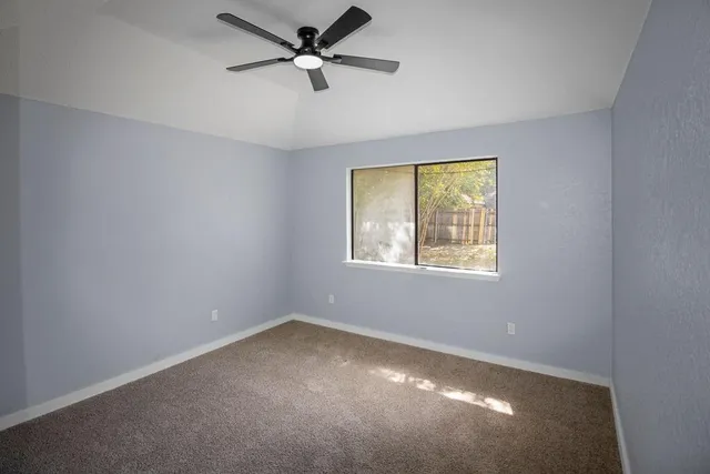 an empty room with a window and a fan