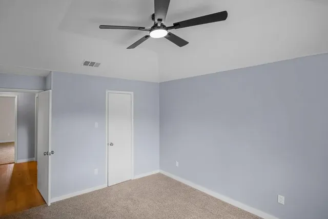an empty room with a ceiling fan and a window