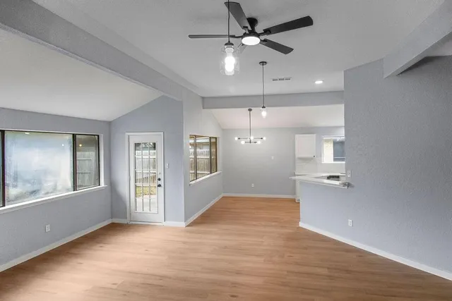 a view of an empty room with a window and wooden floor