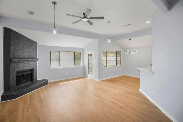 a view of an empty room with a fireplace and a ceiling fan