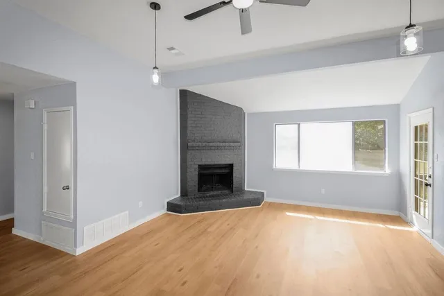 an empty room with windows and fireplace