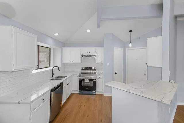 a kitchen with granite countertop a sink stove and refrigerator