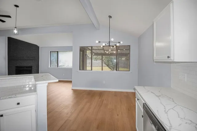 a view of an empty room with a kitchen and a window