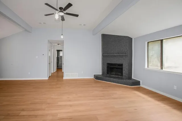 a view of an empty room with a window and fireplace
