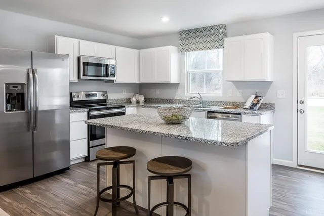 a kitchen with stainless steel appliances granite countertop a table chairs microwave and sink
