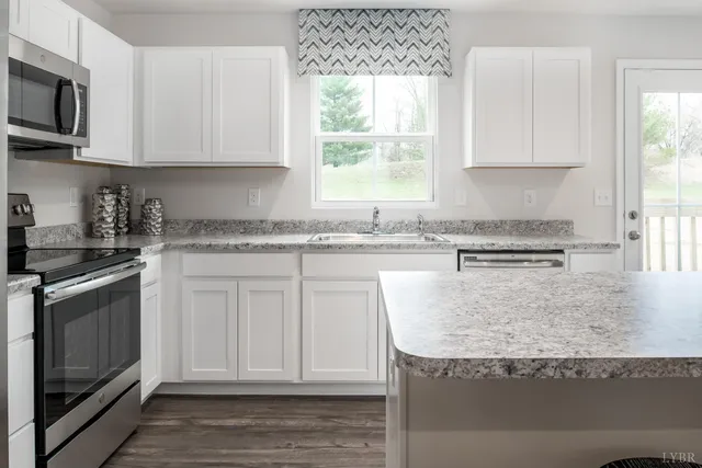 a kitchen with stainless steel appliances granite countertop a stove a sink and a microwave