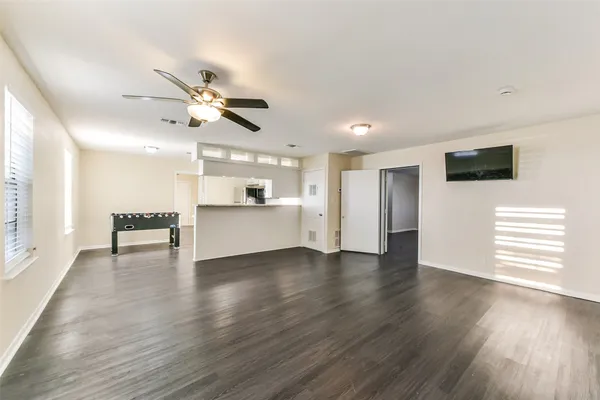 a view of an empty room with a kitchen and wooden floor
