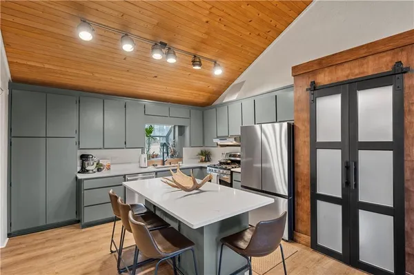 a kitchen with stainless steel appliances granite countertop a dining table chairs refrigerator and cabinets
