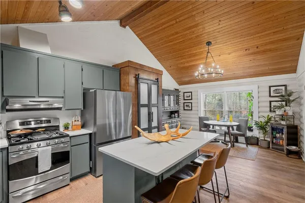 a kitchen with stainless steel appliances granite countertop a stove refrigerator a dining table and chairs with wooden floor