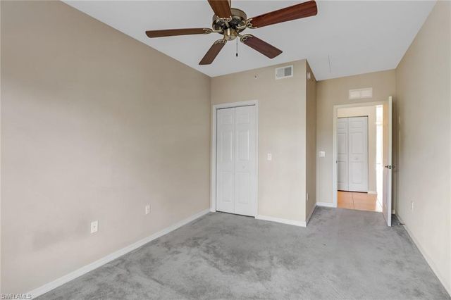 a view of an empty room and chandelier fan