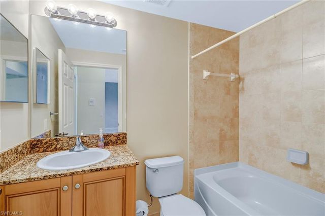 a bathroom with a granite countertop sink a toilet a mirror and shower