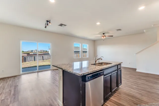 a kitchen with stainless steel appliances granite countertop a sink dishwasher stove and wooden floor