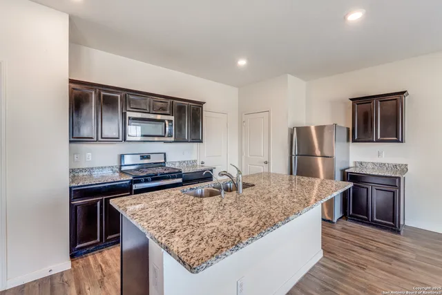 a kitchen with stainless steel appliances granite countertop a sink stove and refrigerator
