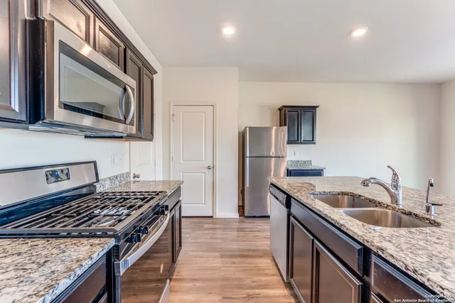 a kitchen that has a sink wooden floor and stainless steel appliances