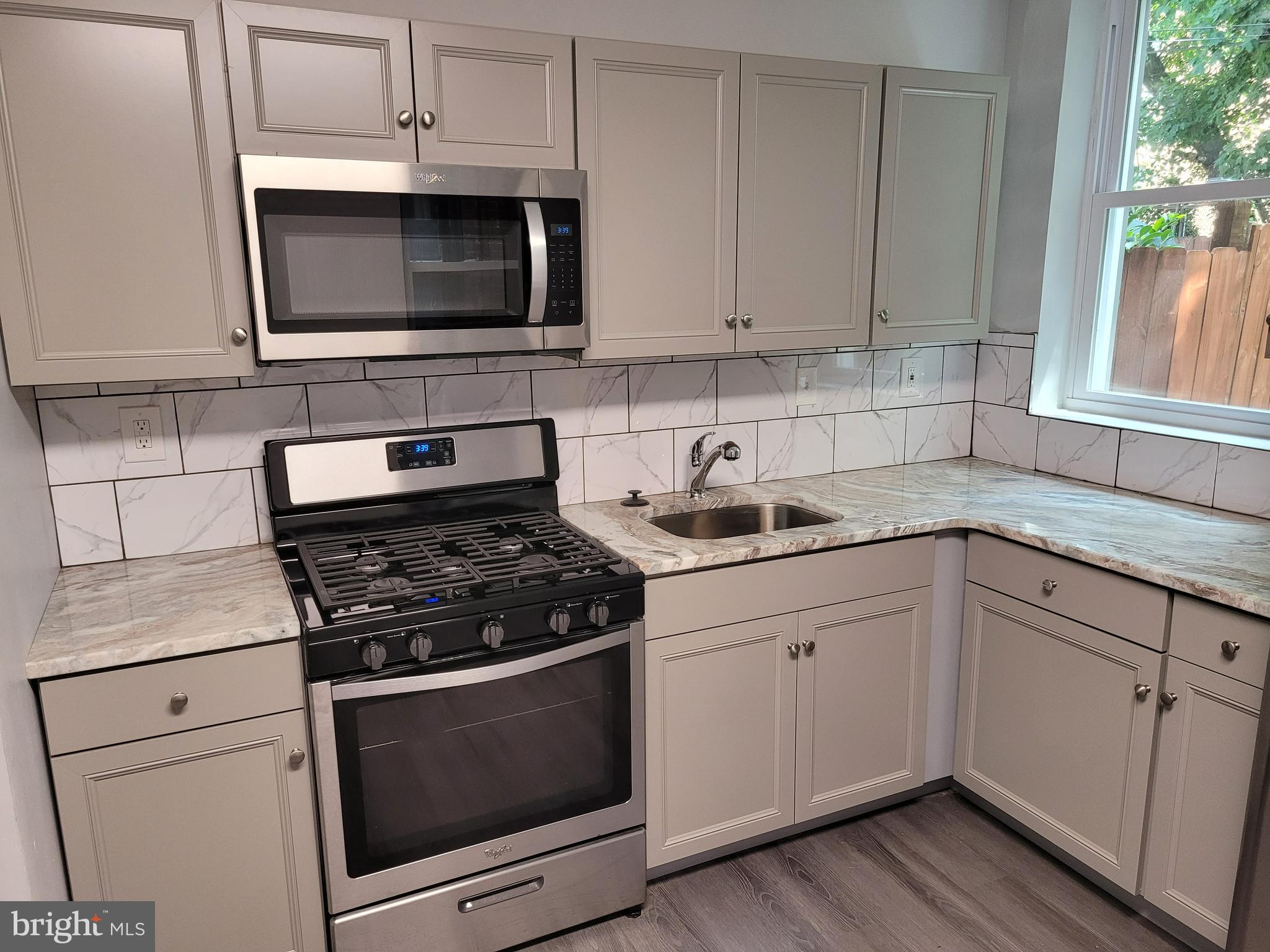 1422 Blavis Street Philadelphia, PA 19140 - Photo 1 of 20 a kitchen with granite countertop white cabinets appliances and a window