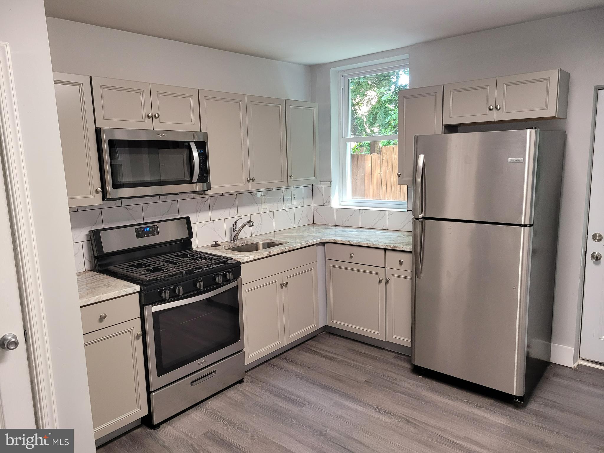 1422 Blavis Street Philadelphia, PA 19140 - Photo 2 of 20 a kitchen with cabinets stainless steel appliances and wooden floor