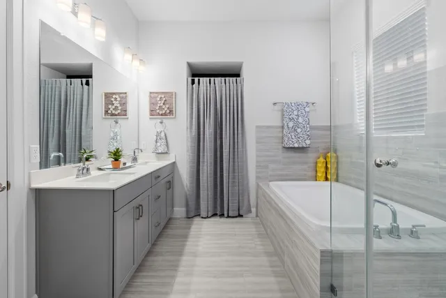 a bathroom with a tub double vanity sink and mirror