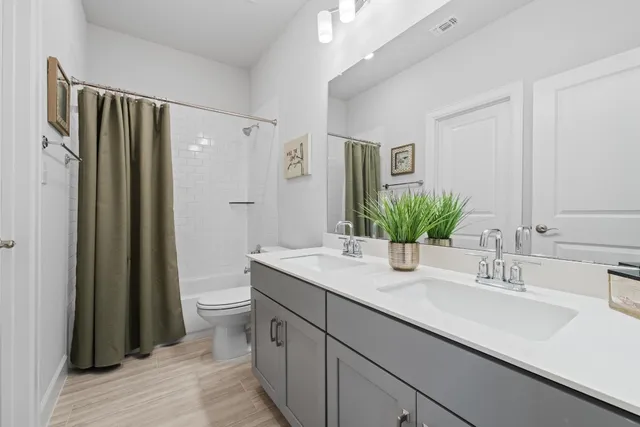 a bathroom with a double vanity sink toilet and shower