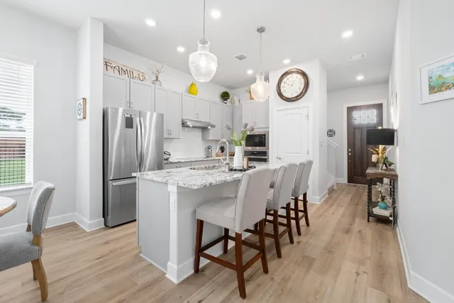 a kitchen with stainless steel appliances granite countertop a table chairs and a refrigerator