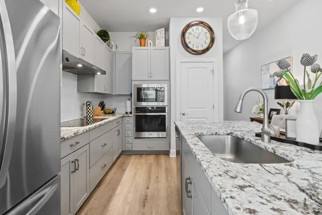 a kitchen with stainless steel appliances granite countertop a sink a stove and a refrigerator