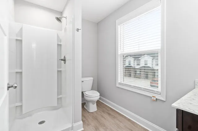 a bathroom with a granite countertop sink a toilet and shower